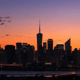 City skyline at dusk with vibrant sunset gradient and glowing tower lights.