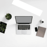 Minimalist desk with open laptop centered on a clean, pale surface.
