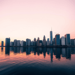 Wide-angle view of a city skyline, pastel sky hues, and crisp building reflections.
